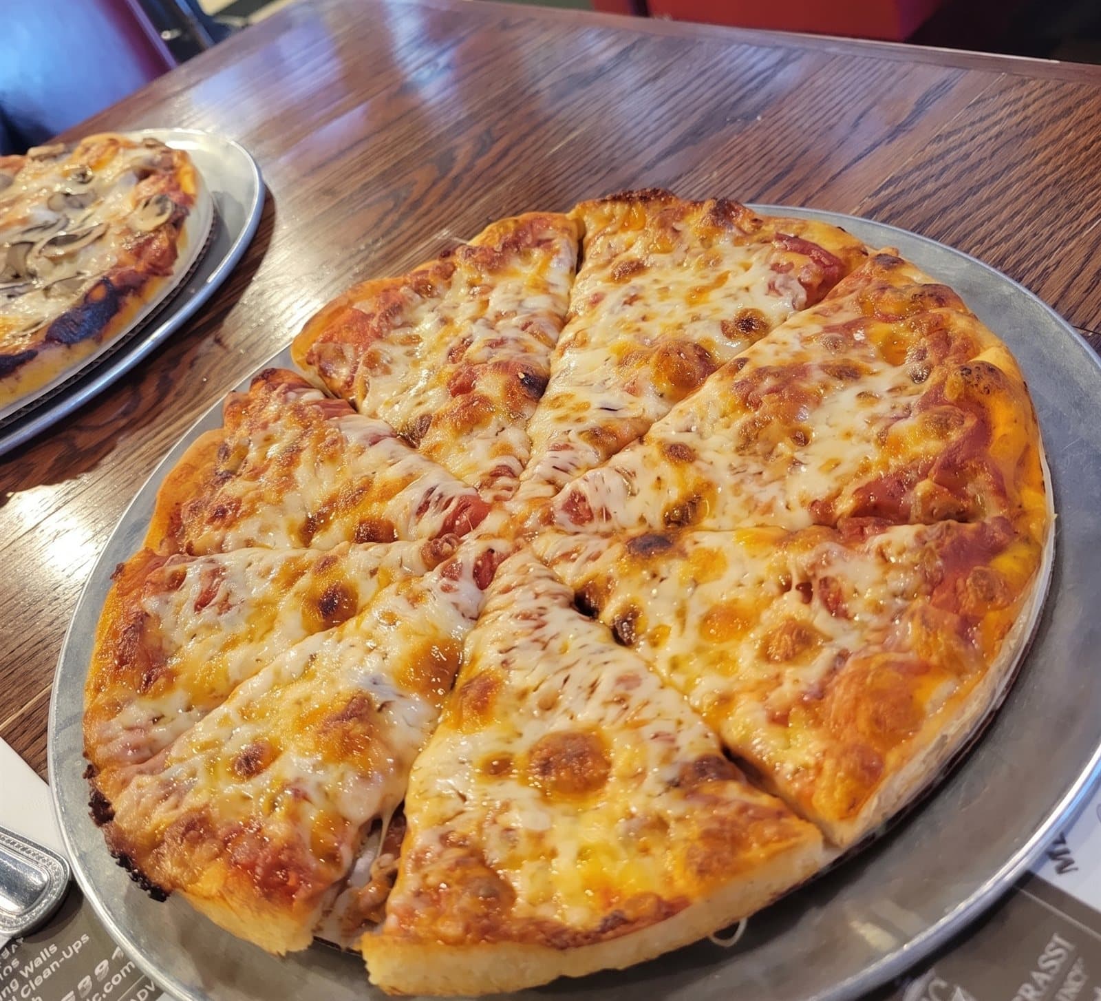 Classic cheese pizza, sliced and golden, on a silver tray at the Central Cafe