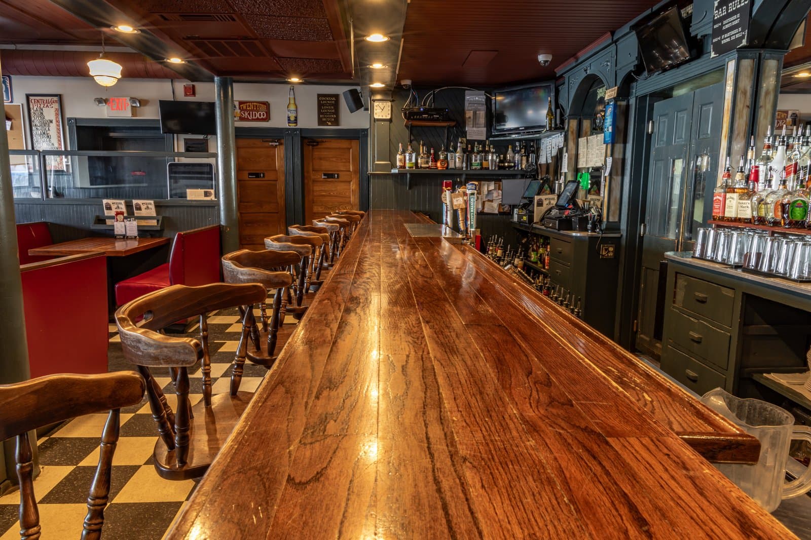The Central Cafe's hundred-year-old mahogany bar, lined with wooden stools on a checkered floor